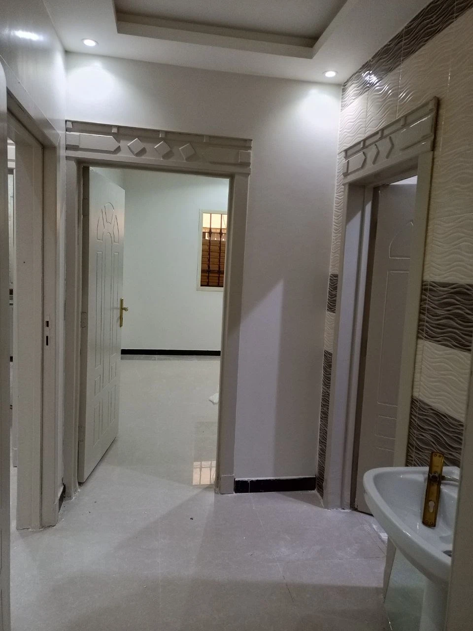 دهانات داخلية لممر المنزل بتشطيب أنيق وجدران بلون فاتح مع سبوت لايت وسيراميك لامع