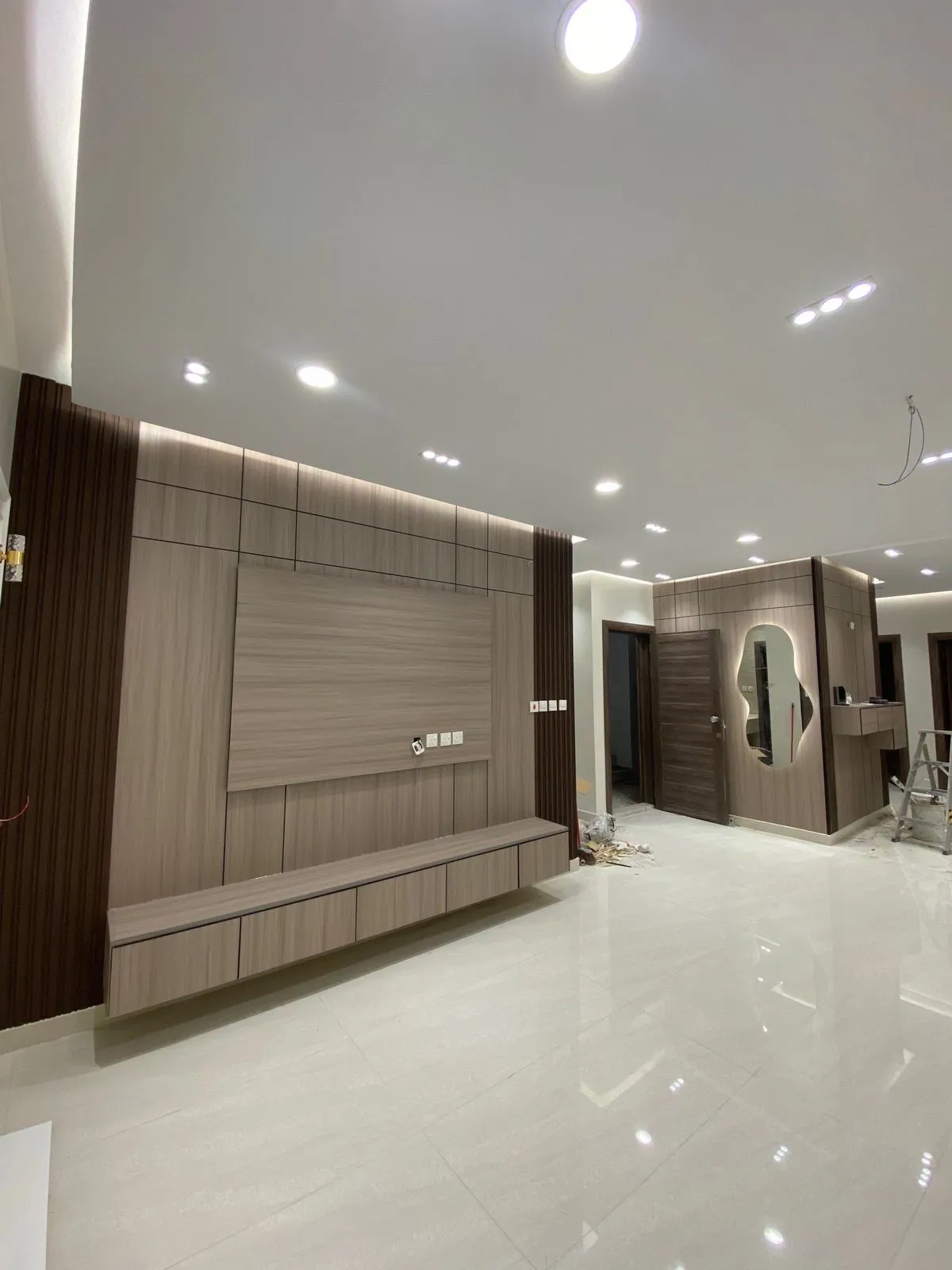 بديل الشيبورد للشاشات ديكور بديل الشيبورد لجدار تلفاز في صالة مع إضاءة سبوت لايت وسقف أبيض