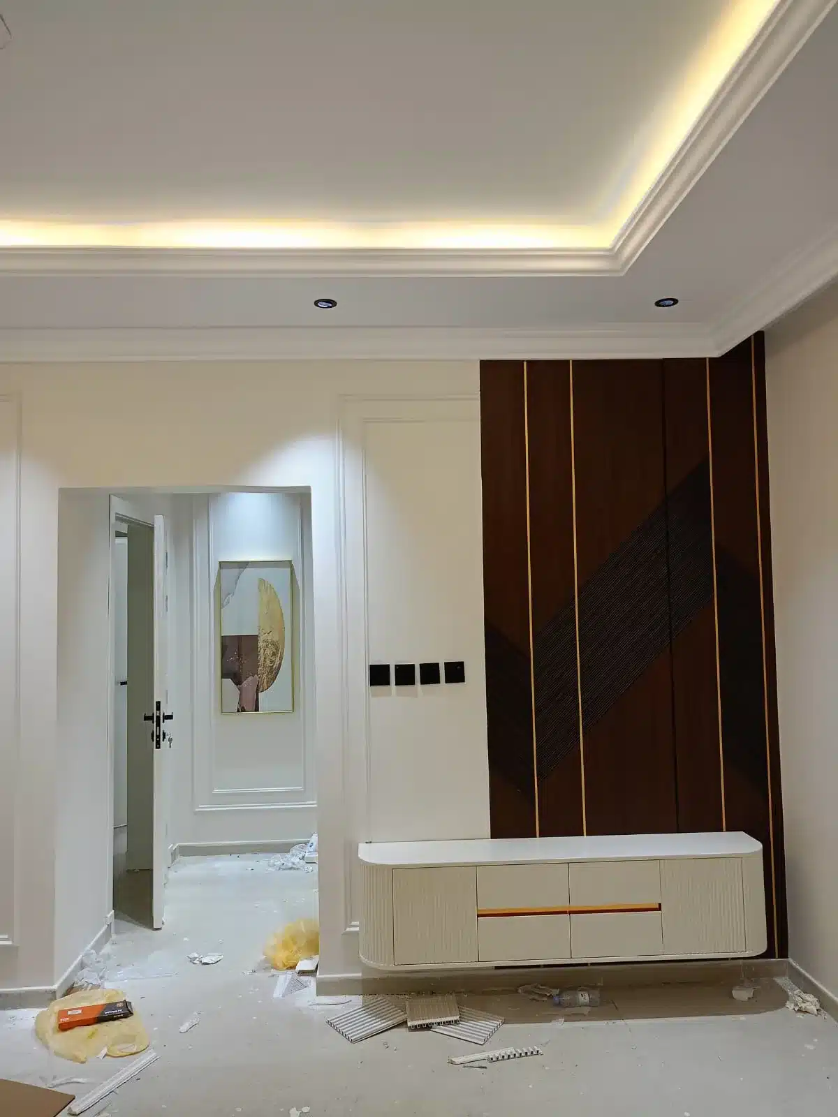 ديكور بديل الشيبورد للتلفزيون خلفية جدارية من بديل الشيبورد في غرفة ذات أرضية بيضاء لامعة وتمديدات كهربائية للتلفزيون