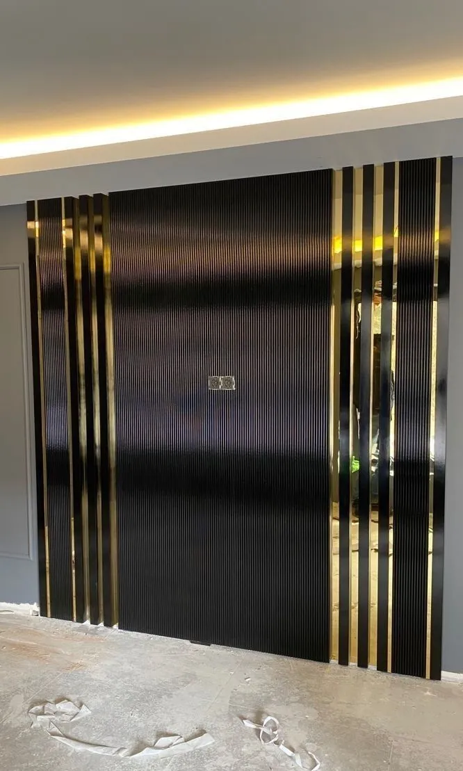 جدار تلفزيون من ألواح بديل الخشب باللون الأسود المضلع مع فواصل ديكورية ذهبية وإضاءة مخفية علوية