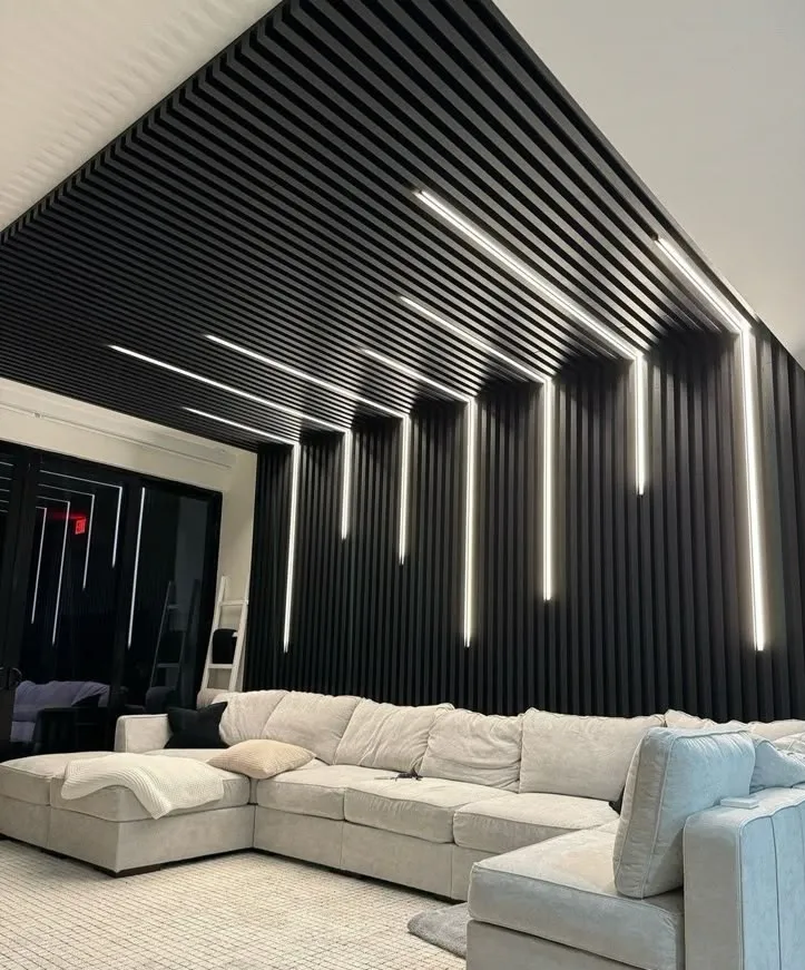 مجلس بجدار وسقف مغطى بألواح بديل الخشب باللون الأسود المضلع مع إضاءة خطية عمودية مخفية