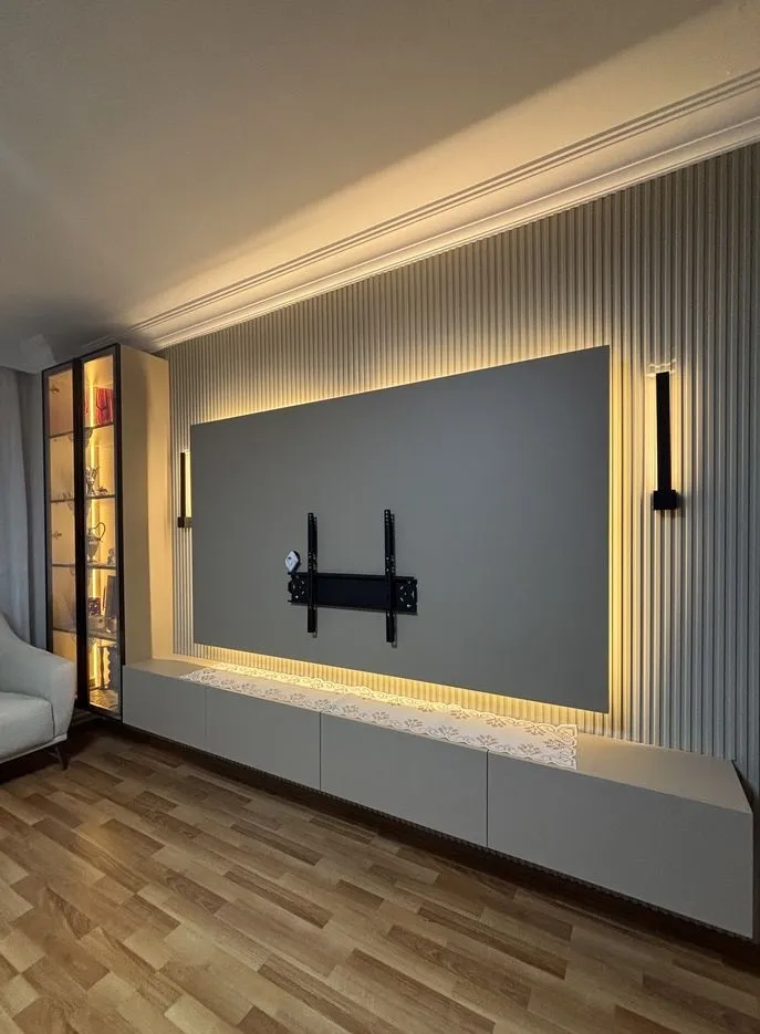 جدار تلفزيون من ألواح بديل الخشب المضلعة باللون البيج مع إضاءة مخفية محيطية ووحدة تخزين سفلية