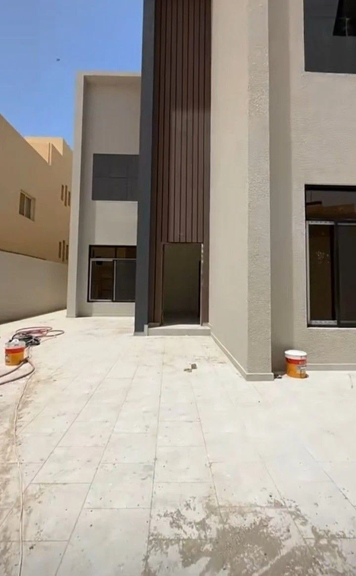 واجهة منزل حديثة بدرجات البيج مع تفاصيل خشبية داكنة بعد تنفيذ أعمال دهان احترافية