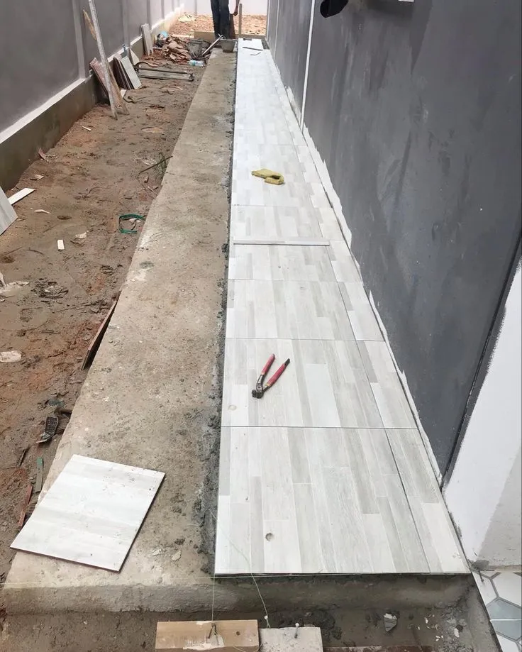 مقاول ترميم الدمام: أعمال تبليط ممر خارجي (حوش) في الدمام ببلاط خشبي فاتح اللون، ضمن خدمات التشطيب والترميم الخارجي.