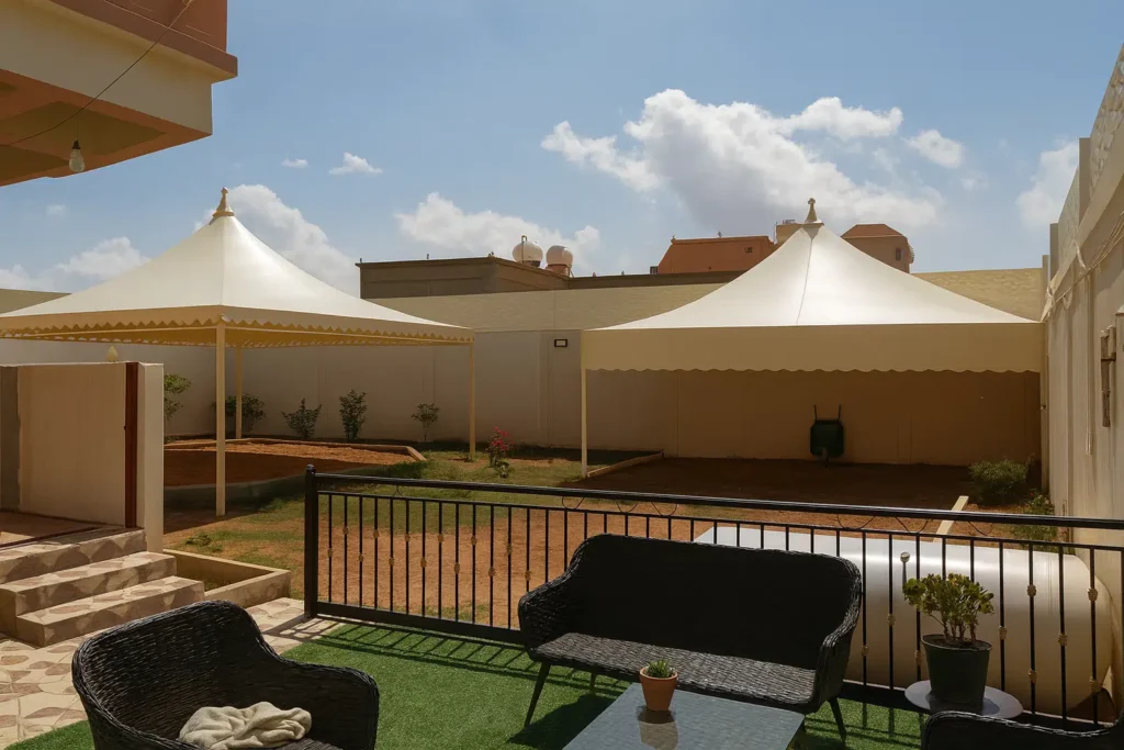 مظلات خارجية كبيرة في حديقة منزلية بالأحساء توفر ظلًا واسعًا مع جلسة خارجية بسيطة من الخيزران