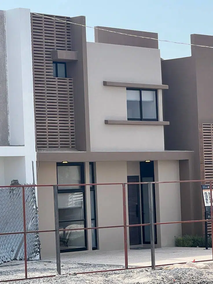 واجهة منزل مودرن بألوان حيادية هادئة تجمع الأبيض والرمادي مع نوافذ داكنة وتصميم أنيق