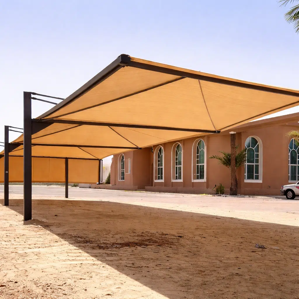 مواقف سيارات خارجية مغطاة بسقوف قماشية بلون رملي مثبتة على أعمدة معدنية سوداء أمام مبنى بواجهة بنية ونوافذ مقوسة