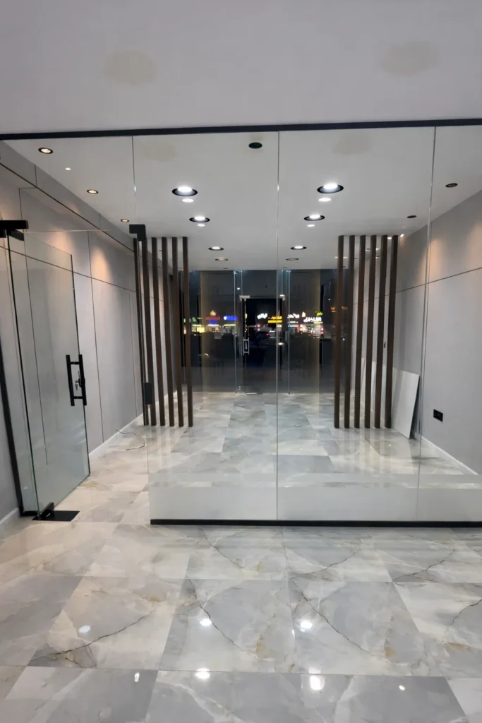 تشطيب داخلي لمحل تجاري تشمل تركيب أرضيات رخام حديثة وجدران زجاجية وديكورات خشبية بالدمام