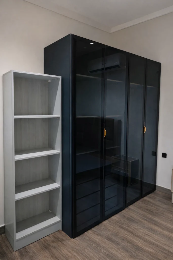 خزانة ملابس مودرن زجاجية بإطارات سوداء مع أرفف جانبية بيضاء مفتوحة في غرفة نوم بأرضية خشبية