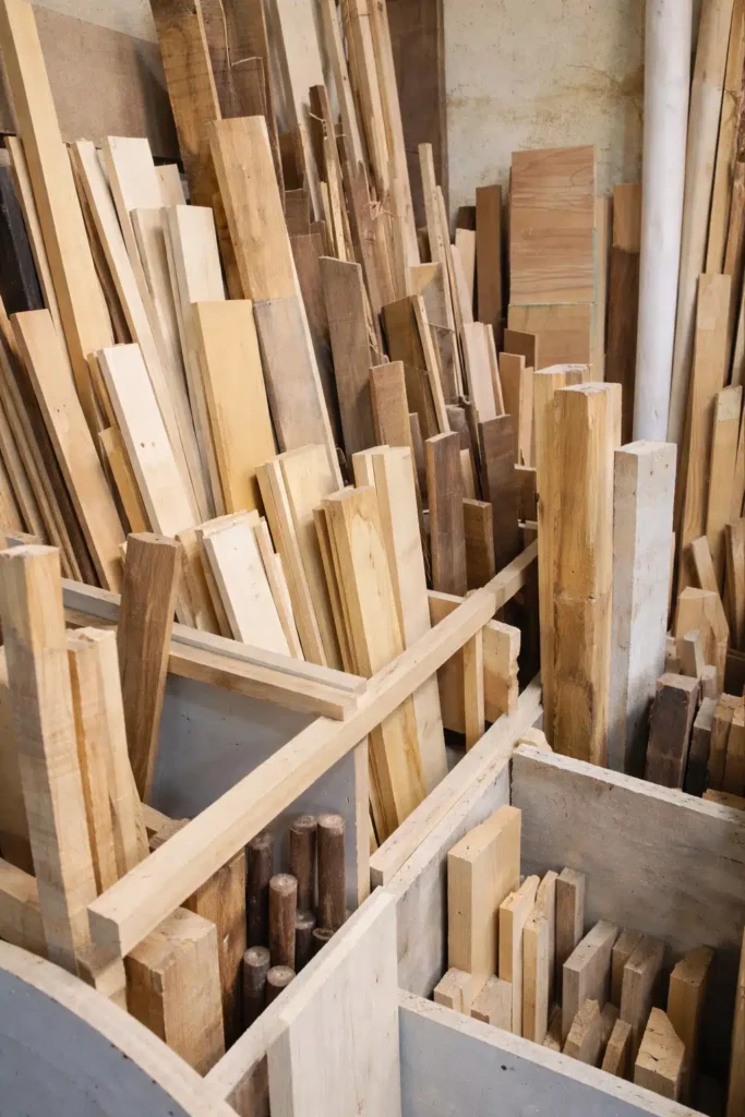 ألواح وخشب مقطوع بأحجام مختلفة مرتبة داخل ورشة نجارة لإظهار تنوع الخامات المستخدمة في تصنيع الأبواب والأثاث الخشبي