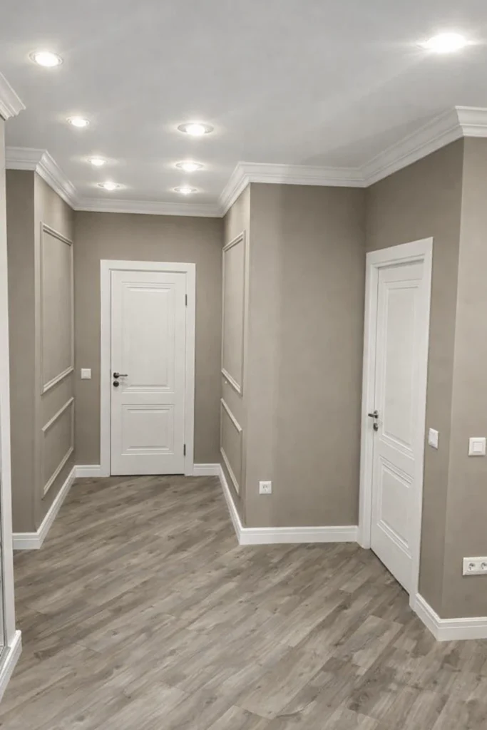 ممر داخلي بديكور بانوهات جدارية كلاسيكية بلون بيج وأبواب بيضاء مع أرضية باركيه وإضاءة سقفية مخفية