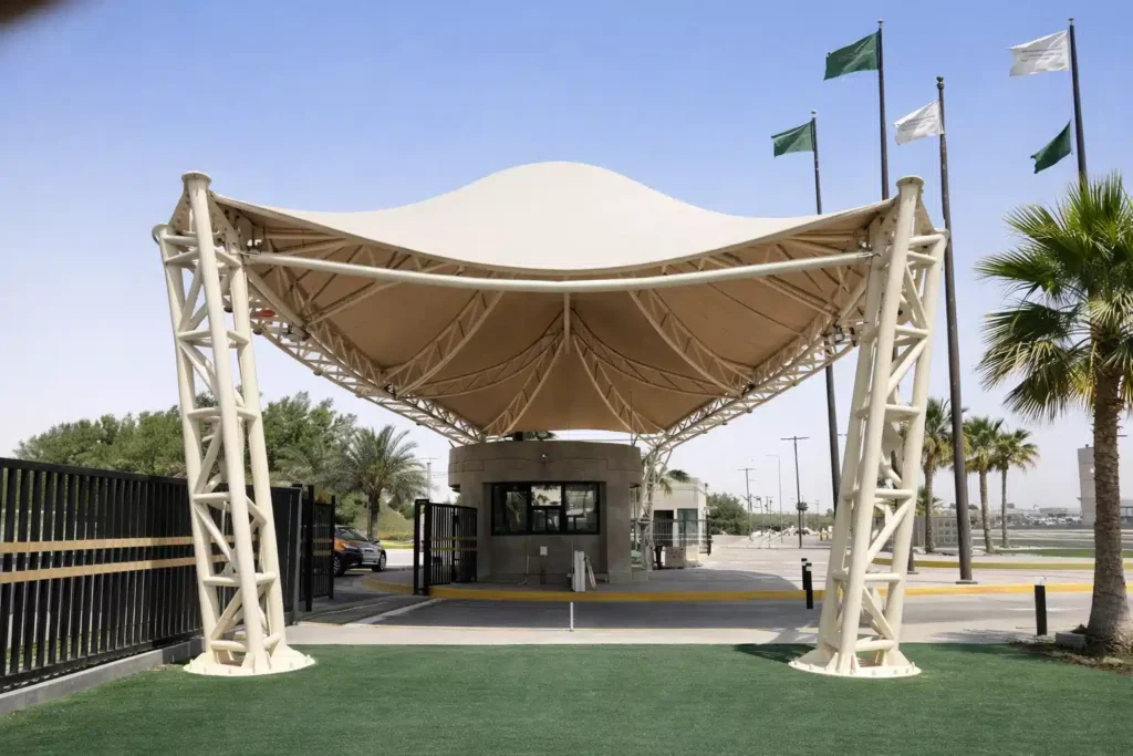 مظلة شد إنشائي كبيرة بتصميم هندسي حديث تغطي مدخل بوابة مع أعمدة معدنية قوية