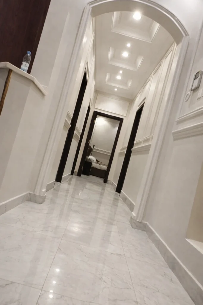 ممر داخلي بديكور كلاسيكي وجدران بطلاء أبيض مع بانوهات جدارية وسقف جبس بورد بإضاءة سبوت